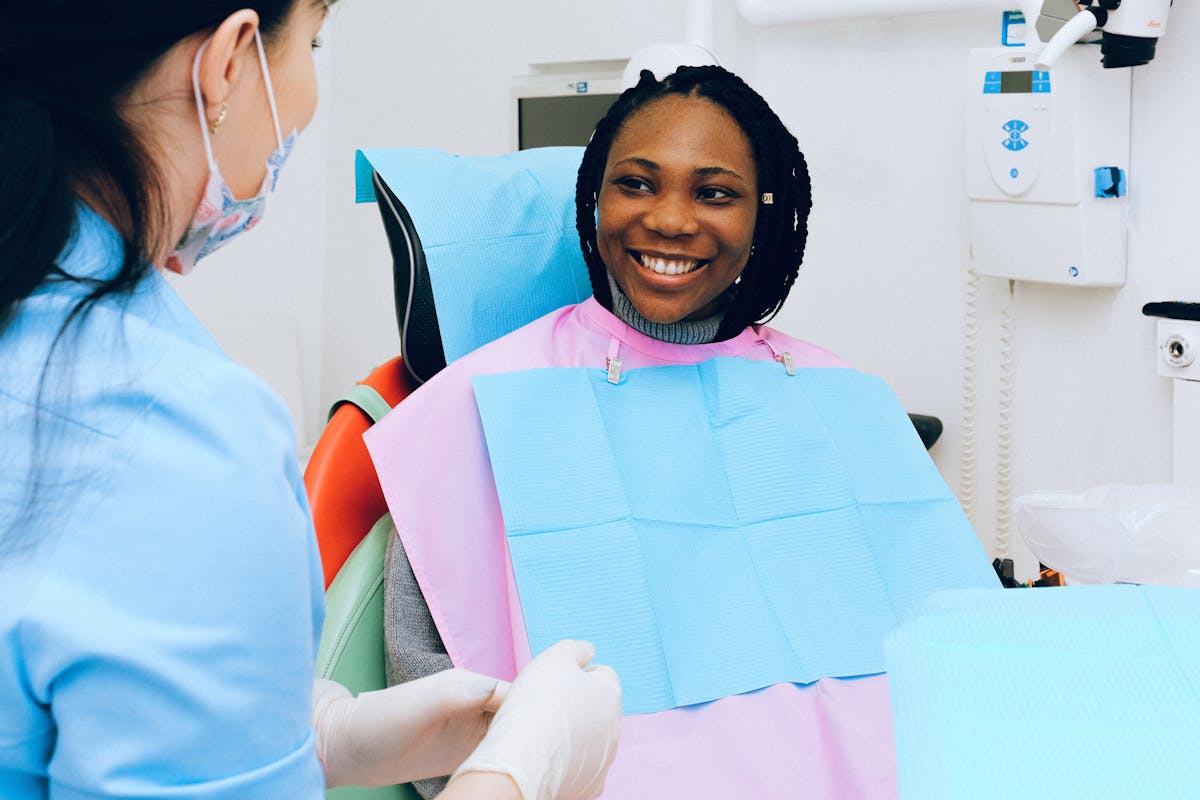 A patient in a dental chair with a paper medical cover discussing with a dentist during a routine checkup