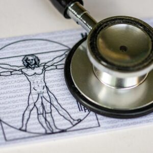 A medical insurance card with the Vitruvian Man printed on it's surface under a stethoscope's chest piece